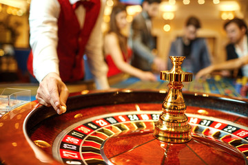 The croupier holds a roulette ball in a casino in his hand. - Powered by Adobe