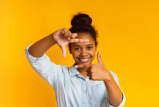 Happy african teenage girl making frame of fingers