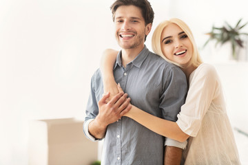 Naklejka premium Young Spouses Hugging Among Moving Boxes In New Apartment
