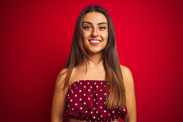 Young beautiful woman wearing casual t-shirt standing over isolated red background with a happy and cool smile on face. Lucky person.
