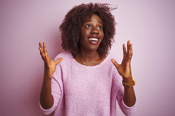 Young african afro woman wearing sweater standing over isolated pink background crazy and mad...