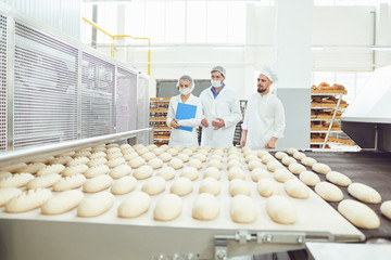 Technologist and baker inspect the bread production line at the bakery