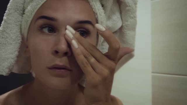 Young woman applying foundation cream after morning shower.