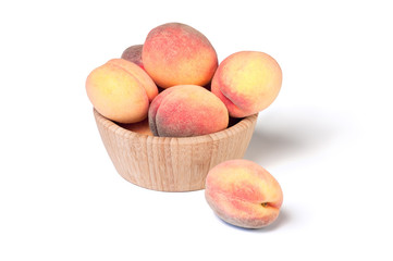 Gentle ripe peaches in wooden bowl isolated on white background.