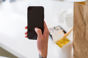 Close upf man using smartphone to orden take away asian food from delivery
