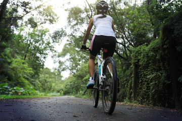 Fototapeta na wymiar Woman cyclist riding mountain bike on tropical rainforest trail