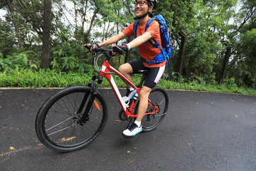 Fototapeta premium Woman cyclist riding mountain bike on tropical rainforest trail