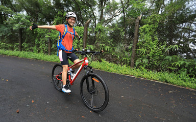 Fototapeta premium Woman cyclist riding mountain bike on tropical rainforest trail