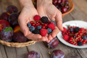 Hands holding fresh berries. Berries in bowls on a wooden table