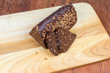 Partly sliced brown bread triangular shape on cutting board closeup