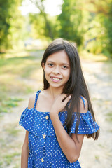 teenager girl in a blue dress walks in the park