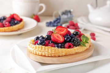 Sweet tartlet with berries on light table