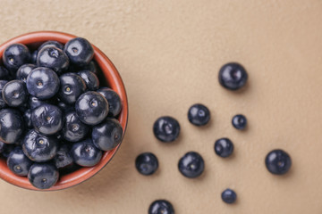 Bowl with fresh acai berries on color background