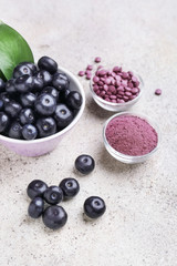 Acai berries with powder and tablets on light background