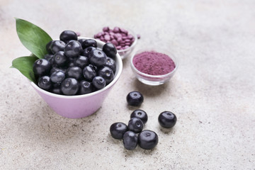 Acai berries with powder and tablets on light background