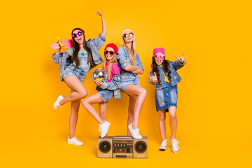 Full length size photo of group of four people carefree students having fun discotheque white parents are absent. Wearing denim outfit showing horned signs isolated yellow background