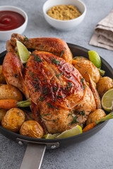 Roast chicken whole. Served on a plate with vegetables and baked potatoes. Front view.