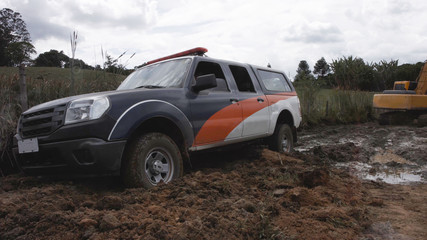 Fototapeta na wymiar police car stuck in a mud road on a farm in the afternoon with cloudy sky - Image