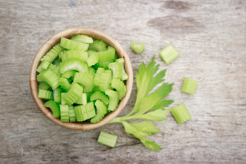 Green celery slices on wooden bowl for healthy eating 