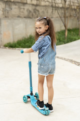 Naklejka premium Back view of girl with blue scooter