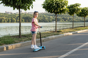 Naklejka premium Back view of girl riding blue scooter