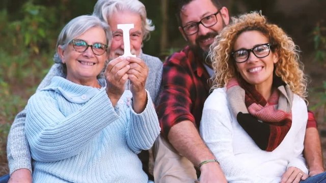 Group of mixed ages generations people smiling and showing blocks letters with  life word -  happy lifestye enjoying the outdoor leisure activity together like a family