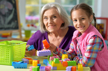 Portrait of grandmother playing with her little granddaughter at home