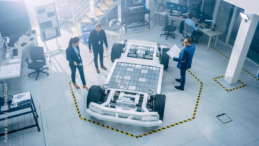 Poster team of automobile design engineers in automotive innovation facility. they are working on electric 