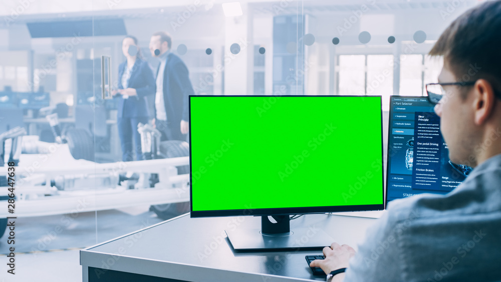 Poster professional engineer works on a computer with green screen mock-up template. electric car chassis p