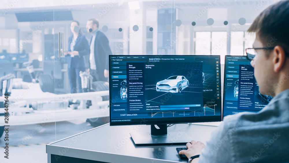 Poster Professional Engineer Works on a Computer with a 3D CAD Software and Tests the Electric Car Chassis Prototype with Wheels, Batteries and Engine Standing in a High Tech Development Laboratory.