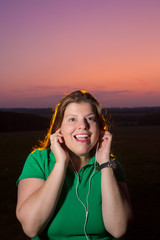 Lady portrait outdoors during twilight with reflection of a yellow back light as the Sun. She is...
