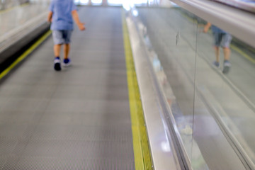 flat straight going escalator with a blurred body parts of a child in the back