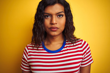Transsexual transgender woman wearing stiped t-shirt over isolated yellow background with a confident expression on smart face thinking serious