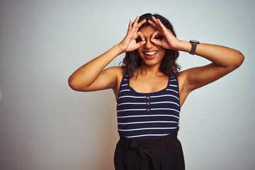Transsexual transgender woman wearing striped t-shirt over isolated white background doing ok gesture like binoculars sticking tongue out, eyes looking through fingers. Crazy expression.