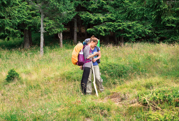 two hiker girls on the forest trail in the mountains looking for a way on the map