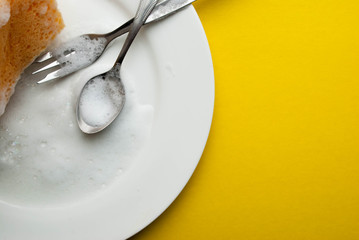 Cleaning sponge on a white plate on a yellow background