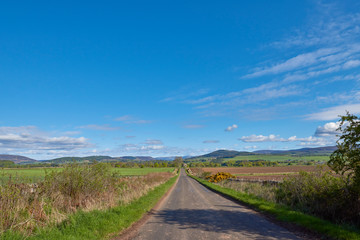 Fototapeta na wymiar Looking towards Glen Prosen in the Angus Glens from a small minor straight road, heading towards Inverharity Castle on a sunny Morning in May.