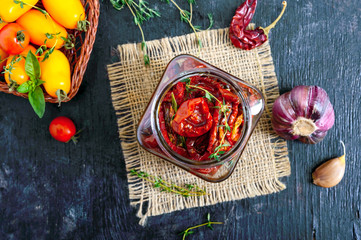 Sun-dried tomatoes with herbs, garlic in olive oil in a glass jar. Top view, flat lay