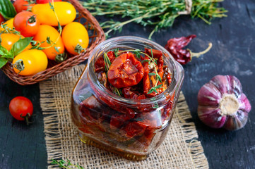 Sun-dried tomatoes with herbs, garlic in olive oil in a glass jar. Top view