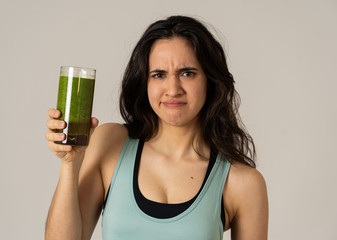 Beautiful young sports latin woman boring of diet holding green smoothie in dislike
