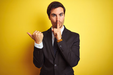 Young handsome businessman wearing suit and tie standing over isolated yellow background asking to...