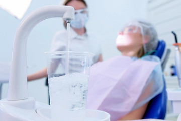 Work in dentistry. Doctor examines woman's teeth and makes consultation. Pouring water in glass in...