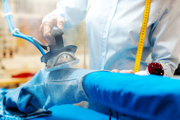 Employee in textile cleaning ironing some trousers