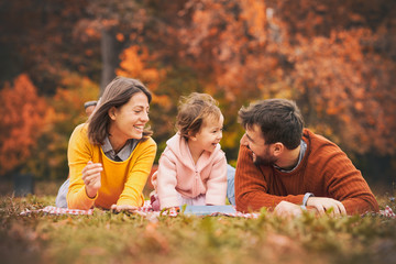 Enjoying every moment together. Happy young family of three smiling while lying on grass in park