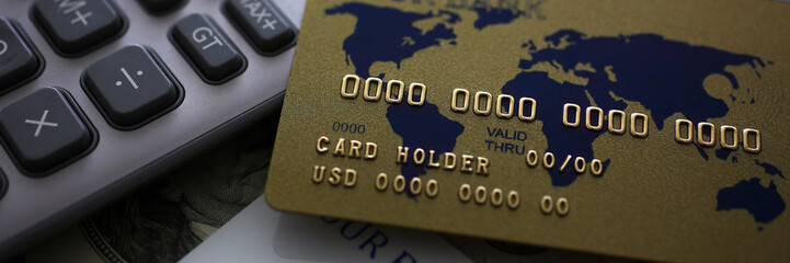 Credit card and calculator lying on big amount of US money closeup