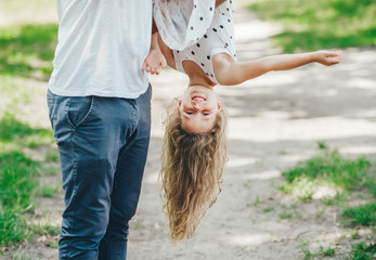 Father letting his laughing daughter fly on his arms.