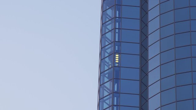 Glass Elevator Going Up the Glazed Facade of Skyscraper and Stop . Glass Curtain Facade Wall Background.
