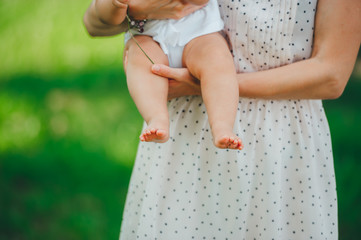 Little bare baby legs. Baby daughter is in mother hands outdoors