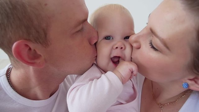 Happy family concept. Parents kissing baby smiling.
