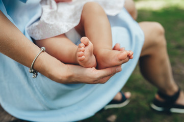 Baby legs in mother hands outdoors